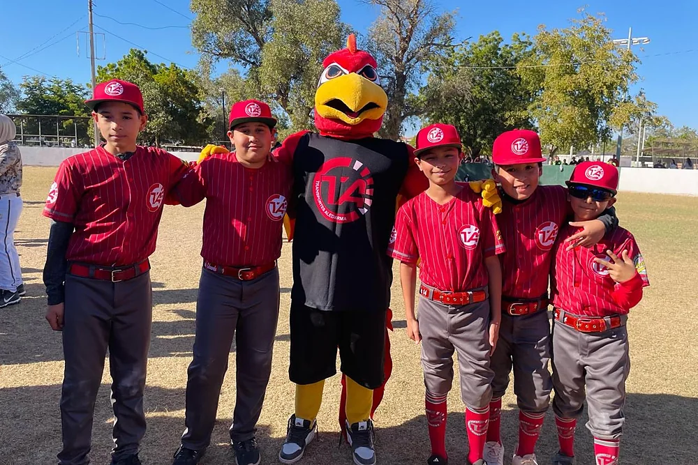 Equipo infantil de beisbol con uniforme de la empresa, junto a la mascota